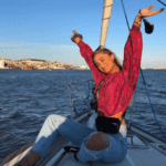 A Young Woman On A Boat Smiling And Holding Her Arms Up