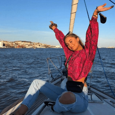 a young woman on a boat smiling and holding her arms up